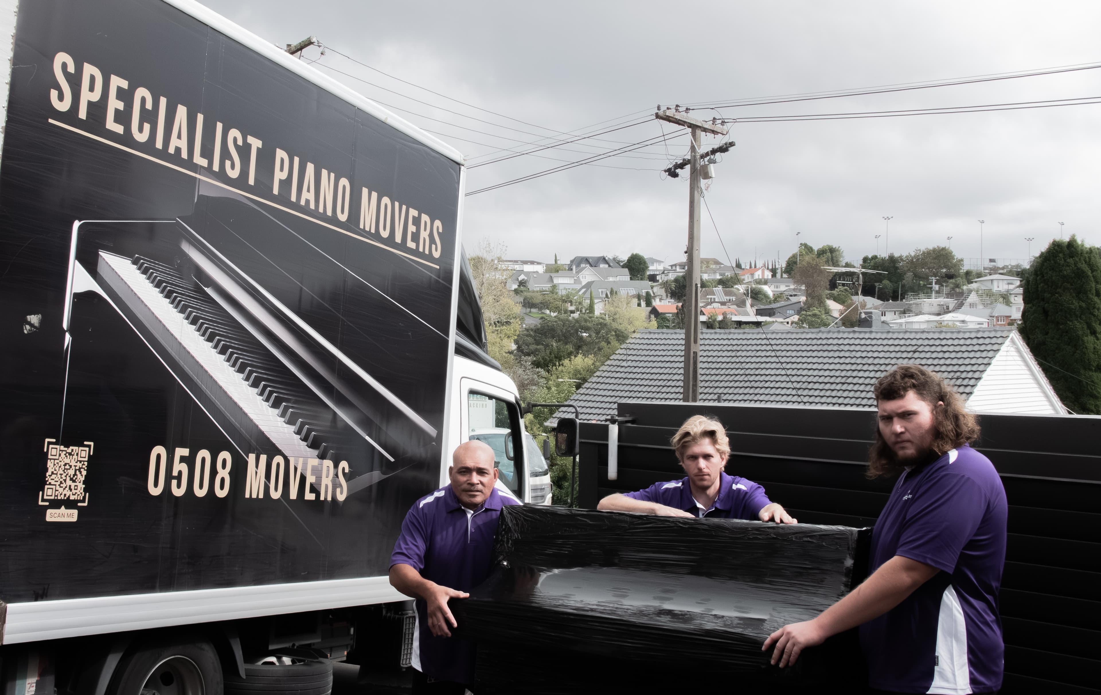 Specialist Movers crew loading a wrapped piano into the truck