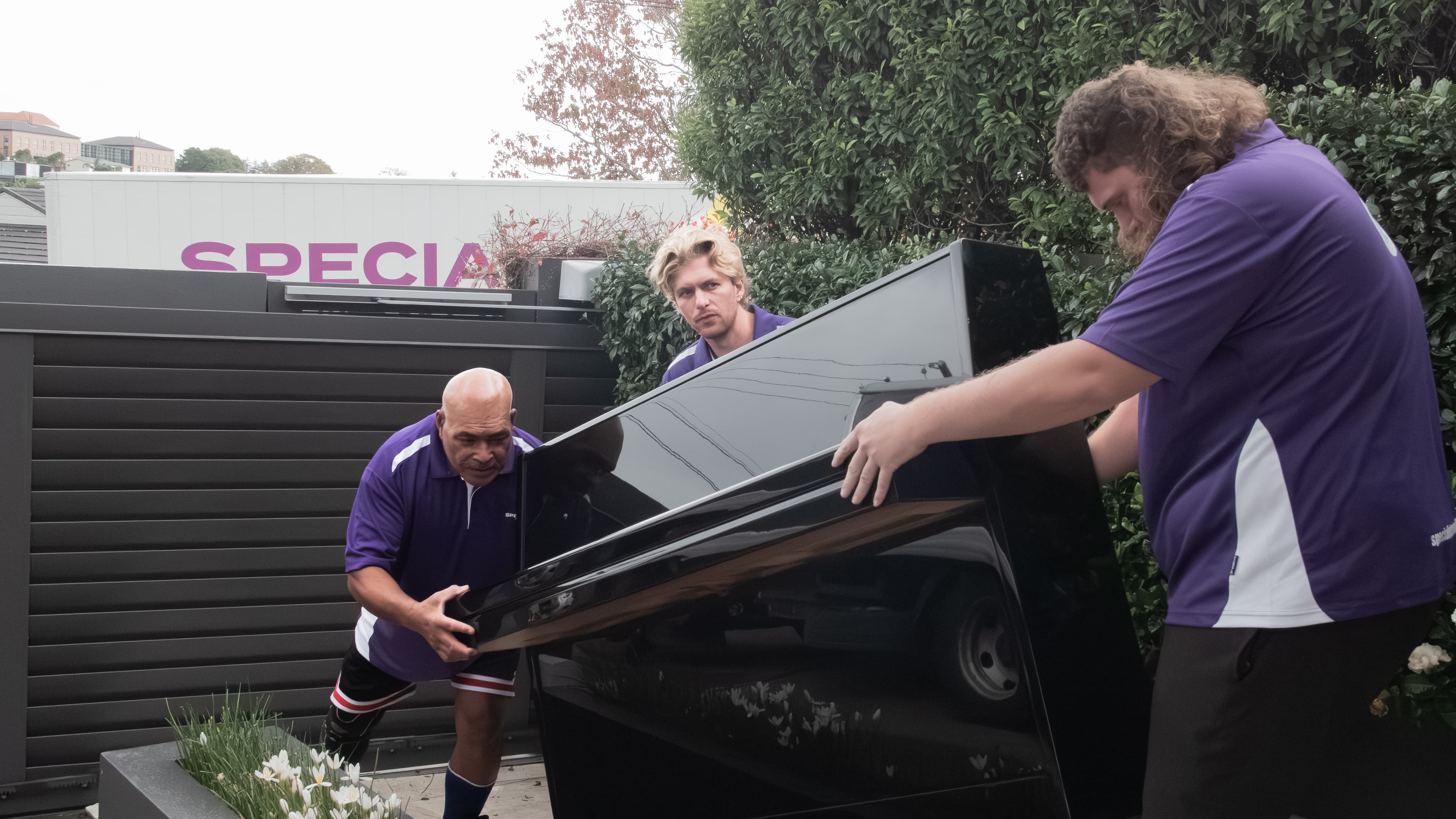 Specialist Movers crew handling a wrapped piano inside a home